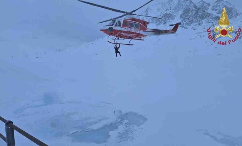 helicopter lowers rescuer over lake in Alps